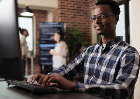 Smiling confident african american software engineer developing machine learning algorithm in order to sustain system security stability. Cyber developer creating network using binary encryption.
